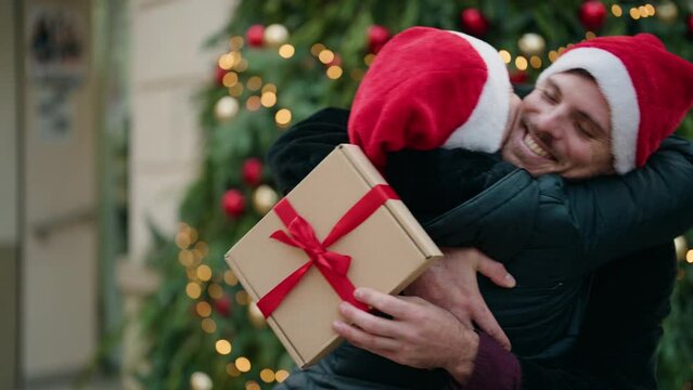 Mother and son wearing christmas hat surprise with gift at park