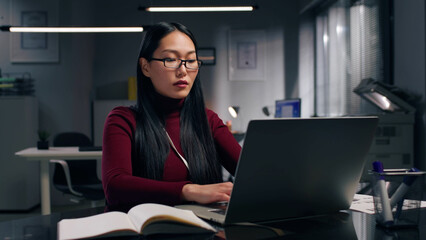 Confident asian entrepreneur typing on computer in modern office. 