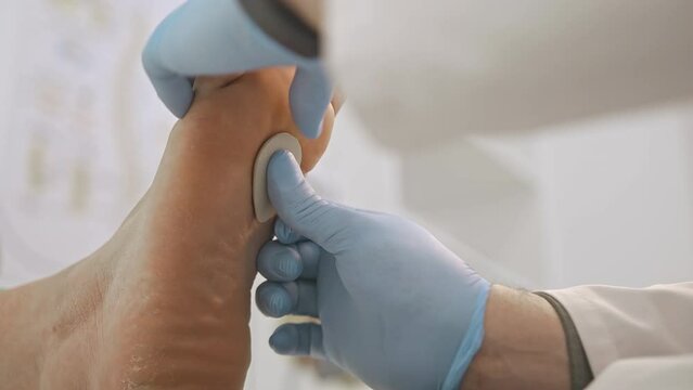 The doctor receives the patient in the office of the clinic of podology and orthopedics. Makes a primary examination of the foot, flat feet, curvature of the leg, applies a stone to the foot