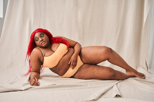 Body positive young woman looking relaxed while lying shirtless at the floor