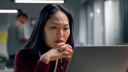 Close up portrait of stressed businesswoman sitting in office and looking at laptop screen. 