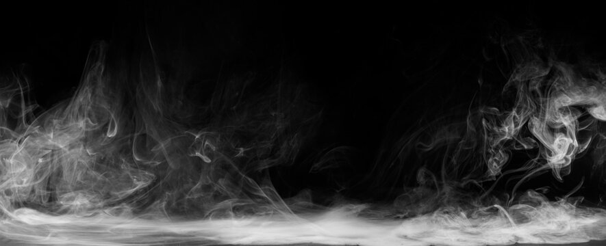 Abstract colored smoke moves on black background. Mystical swirling smoke rolling low across the ground.