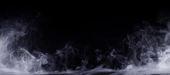 Abstract colored smoke moves on black background. Mystical swirling smoke rolling low across the ground.