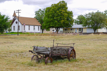 Old carriage on lawn and church in Antelope, Oregon, USA