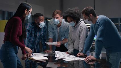 Diverse business colleagues wearing face mask having meeting in office. 