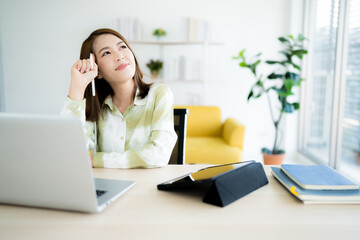 Obraz premium A photo of a bright Asian business woman working at home in the room. The idea is Work form Home Finance Marketing Bright Portrait Simple