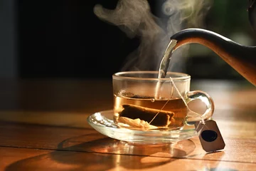 Foto op Aluminium hot water pouring into transparent cup with tea bag © taveesaksri