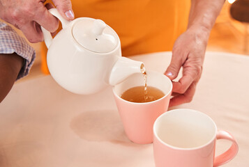 Caucasian woman pouring tea into the cups while preparing having breakfast