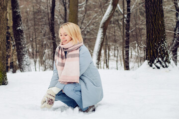 Fototapeta premium Outdoors portrait of young beautiful woman girl with blond hair and blue warmcoat having fun and smile in winter park