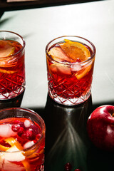 Cocktail with pomegranate juice and ice in a glass on a light green background