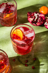 Cocktail with pomegranate juice and ice in a glass on a light green background