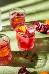Cocktail with pomegranate juice and ice in a glass on a light green background