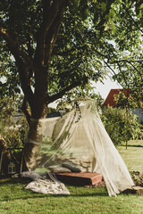 tent made of transparent fabric, trestle bed and pillows under the tree 