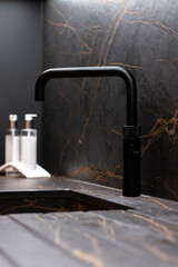 Modern black kitchen tap against marble wall