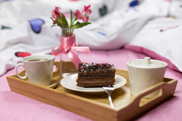 breakfast in bed with a slice of chocolate cake on a wooden tray. Selective focus.