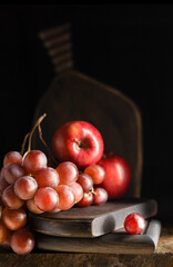 Large grapes and apples on a wooden textured board. Selective focus.
