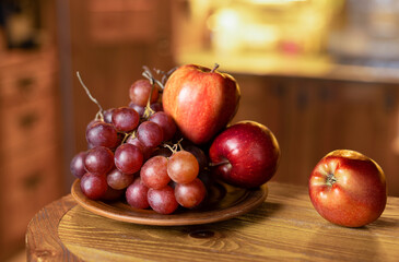 Fruit plate with grapes and red apples on a rustic clay plate. Selective focus.