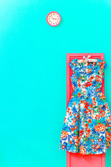 ミントグリーンの壁にピンク色の時計と花柄ワンピースのある部屋