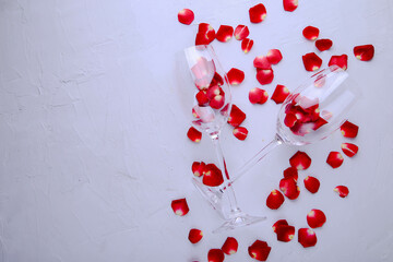 Glasses with rose petals on a gray background with space for text