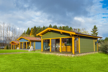 Cottage village on the background of a beautiful sky. One-story houses on lawns. Autumn in the cottage village. Private houses with terraces. Panoramic Windows of buildings.