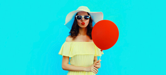 Portrait of beautiful young woman blowing her lips sending air kiss with red balloon wearing a...