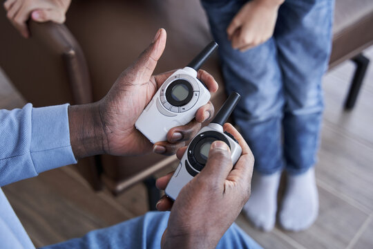 Man holding two walkie-talkie in the both hands while playing with his caucasian son