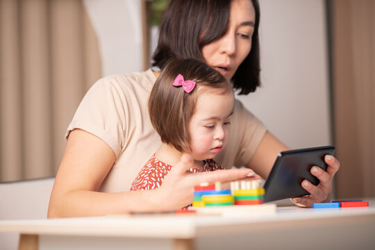 mom and child with down syndrome on online classes with mobile tablet