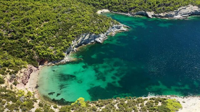 Aerial drone video of famous small bay of Agalipa with crystal clear emerald sea featuring iconic wooden shipwreck left ashore, Skyros island, Sporades, Greece