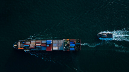 Aerial top view container cargo ship and tugboat full speed carrying commercial container import...