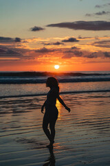 vertical portrait, Silhouette of a woman enjoying a sunset on a beach in Costa Rica.