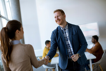 Obraz premium Young business partners making handshake in an office