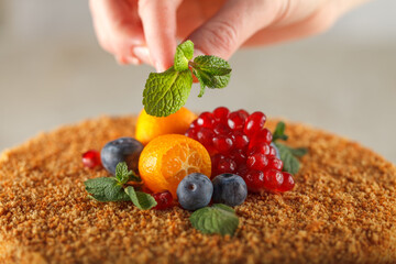 Honey cake with caramel for diabetics decorated with orange, mint, pomegranate slices and blueberries