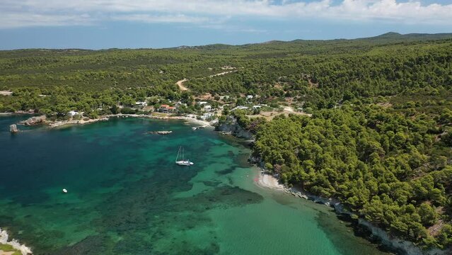 Aerial drone video of famous bay and small traditional village of Atsitsa covered in pine trees and natural sandy beaches, Skyros island, Sporades, Greece