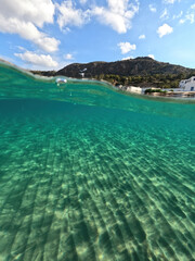Obraz premium Underwater split photo taken from beautiful emerald bay and beach of Kapsali and famous Monastery of Saint John at the background, Kythira island, Ionian, Greece