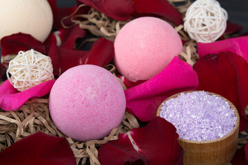 surrounded by red rose petals, in the form of a bomb and crumbly lilac bath salt, in a wooden jar, for relaxation