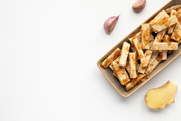 Marinated tofu strips with ginger, garlic, soy sauce and honey marinate on plates.
