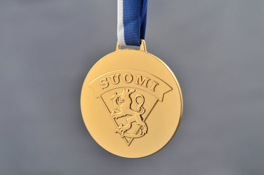 A closeup of a shiny gold medal with the logo of the Finnish Ice Hockey Association.
