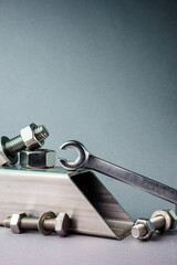 Wrench with nuts and bolts. On a gray background.