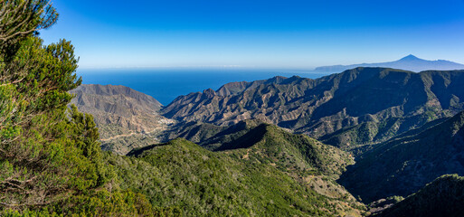Fototapeta na wymiar Wanderurlaub auf LA GOMERA, Kanarische Inseln: Panoramablick von Frau vom Mirador bei Wanderung im Lorbeerwald, Nationalpark Garajonay auf Vallehermoso, Teide im Hintergrund