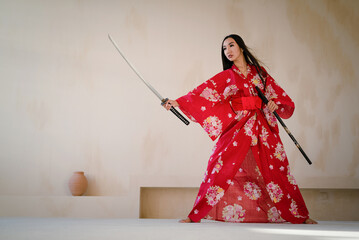 A young girl in the red kimono with the katana sword. The woman warrior concept.