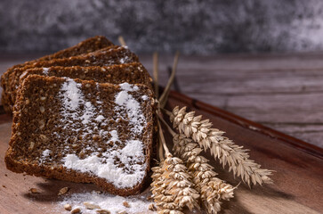 dark bread and wheat ears on wooden background