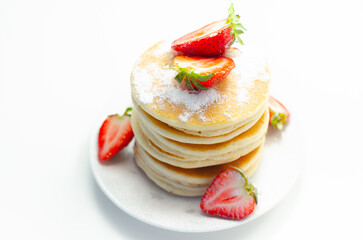 Delicious pancakes stacked with fresh sweet strawberries sprinkled with powdered sugar