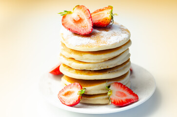 Delicious pancakes stacked with fresh sweet strawberries sprinkled with powdered sugar