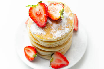 Delicious pancakes stacked with fresh sweet strawberries sprinkled with powdered sugar