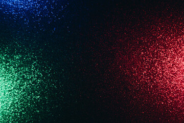 Color glow background. Blur glitter texture. Party illumination. Defocused neon green red blue shimmering sparkles pattern on dark black abstract overlay.