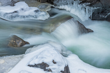 Winter landscape of a cascade on Boulder Creek captured with motion blur and framed by ice, Front Range, Rocky Mountains, Colorado, USA