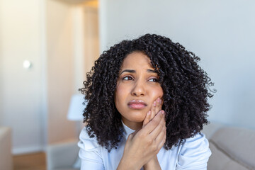 Fototapeta na wymiar Portrait of unhappy African-American woman suffering from toothache at home. Healthcare, dental health and problem concept. Stock photo