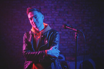 A singer man at the scene with the microphone in the neon lights concept.