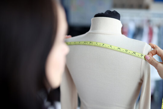 Woman fashion designer takes measurements with centimeter