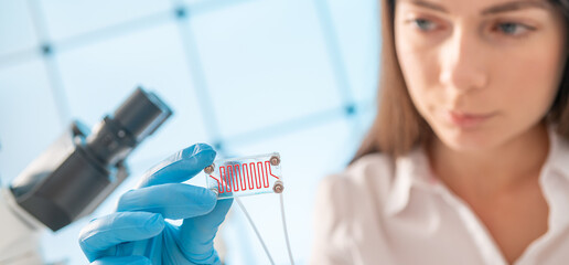 Woman in the laboratory holds in her hand lab on chip device. microfluidics device
